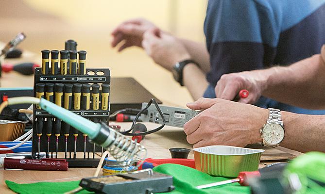 Hands repair an electronic device