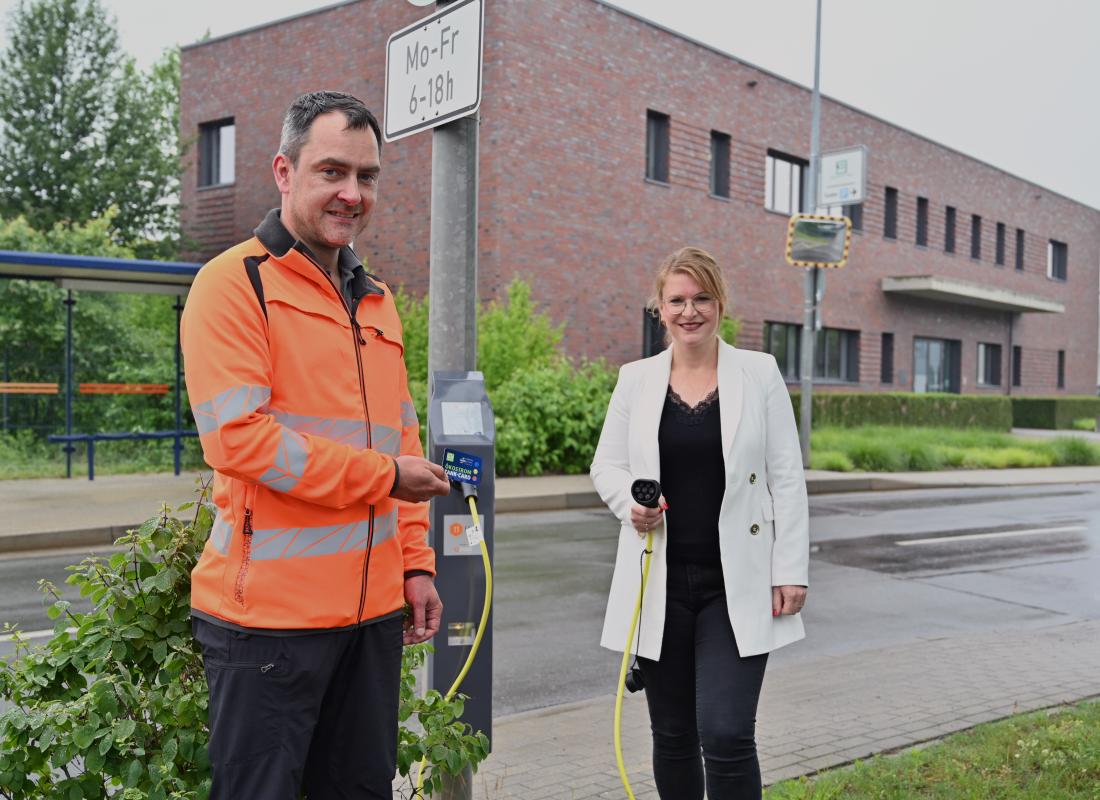 Wolfgang Hillesheim, Verantwortlicher für Verkehrssteuerung beim KSJ, und Djamila Neutert, Teamleiterin Energiedienstleistungen bei den Stadtwerken Energie, an der ersten Straßenlaterne der Stadt, die mit einem E-Ladepunkt ausgestattet ist